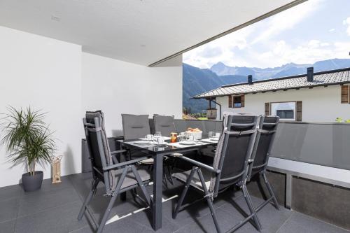 a dining table and chairs on a balcony with mountains at Apart Alina in Schwendau