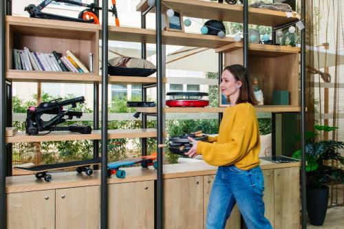 a woman walking in front of a shelf with skateboards at Aparthotel Adagio Lille Centre Grand Place in Lille