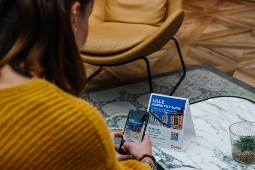 a woman holding a cell phone in her hand at Aparthotel Adagio Lille Centre Grand Place in Lille