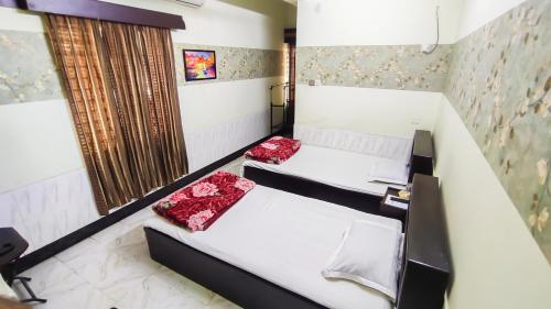 a bedroom with two beds and a window at HOTEL HERITAGE in Chittagong