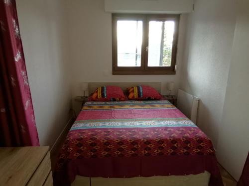 un lit dans une petite pièce avec une fenêtre dans l'établissement Bel Appartement face au paleospace, à Villers-sur-Mer