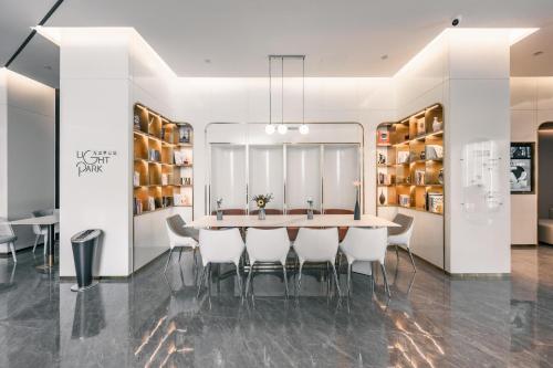 a dining room with a table and white chairs at Atour Light Zhengzhou West Longhai Road Subway Station in Zhengzhou