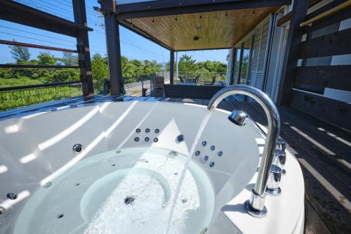 a jacuzzi tub on the deck of a house at Beach Side Secret -SEVEN Hotels and Resorts- in Ginoza