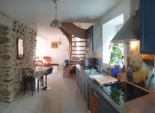 a kitchen with a table and a spiral staircase at Le Baco, gîte à la ferme in Coublevie