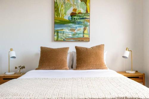 a bed with two lamps and a painting on the wall at Iconic Mid-century modern, waterfront apartment in Geelong