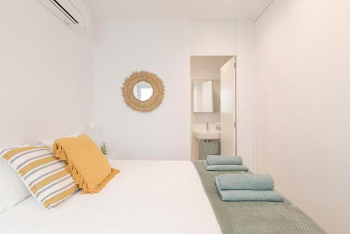 ein weißes Zimmer mit einem Bett mit Kissen und einem Spiegel in der Unterkunft Marsalada - Ground floor front line beach apartment in Playa de Mar