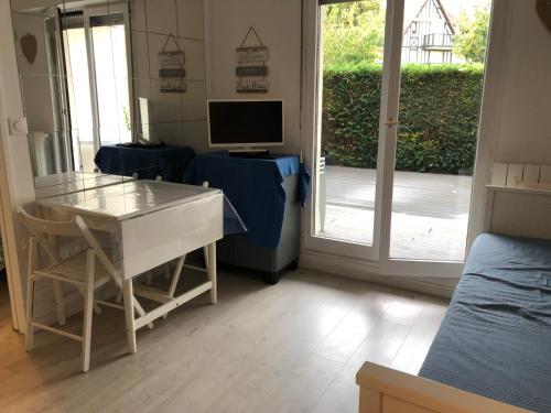 Cette chambre comprend un bureau, une télévision et une porte. dans l'établissement Les Dunes de Cabourg 100m plage, à Cabourg