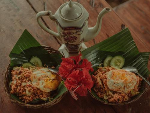 a table with two dishes of food and a teapot at Da'kayu Glamping in Munduk
