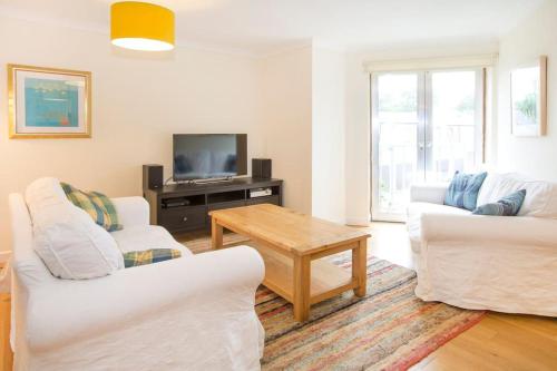 a living room with two white chairs and a television at Bright Oxford Apartment in Oxford