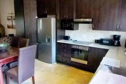 une cuisine avec un réfrigérateur en acier inoxydable et une table dans l'établissement Bee-Eater Cottage, DaGama Dam, à White River