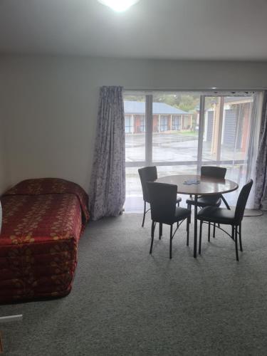 a bedroom with a bed and a table and chairs at Arran Motel in Te Anau