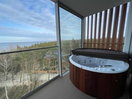 a bath tub in a room with a large window at PINEA Apartments Pobierowo z niesamowitym widokiem na morze oraz jacuzzi w wybranych apartamentach in Pobierowo