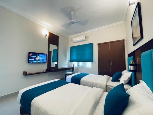 a hotel room with three beds and a flat screen tv at The Oval House, Kochi - Approved by Kerala Tourism - Exclusively for Families in Cochin