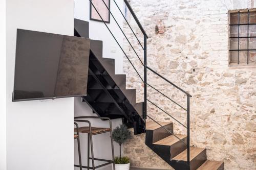 a living room with a staircase with a flat screen tv at Apartamentos BocairentHomes, en pleno centro de Bocairent, con pequeña piscina y parking privado in Bocairent