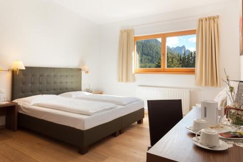 a bedroom with a bed and a table and a window at Hotel Sole - Sonne in Dobbiaco