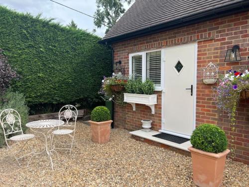 a patio with a table and chairs and a white door at Boutique style self contained annexe with garden in Mursley