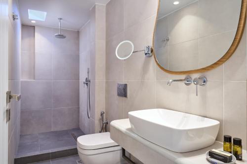 a bathroom with a sink and a toilet and a mirror at Meltemi Village Hotel in Perissa