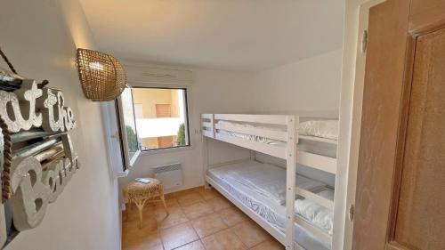サント・マキシムにあるLes Pins Bleusの小さな客室で、二段ベッド1組(白い棚付)が備わります。