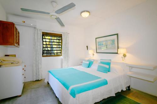 a bedroom with a bed with blue pillows and a ceiling fan at La Case Najoli in Choisy