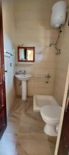 een badkamer met een toilet, een wastafel en een bad bij Nour El Waha Hotel in Siwa