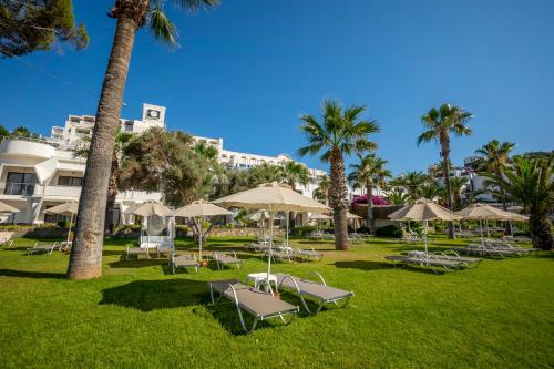 a park with lounge chairs and umbrellas and palm trees at Azka Hotel in Bodrum City