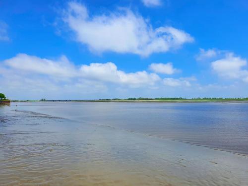 a body of water with a blue sky and clouds at Stylische Wohnung mit Weitblick und großem Balkon in Karolinenkoog