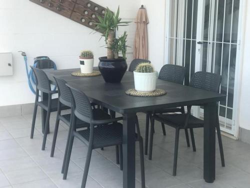 una mesa de comedor negra con sillas y macetas en Nova Beach Super cool seaview apartment, en Santa Pola