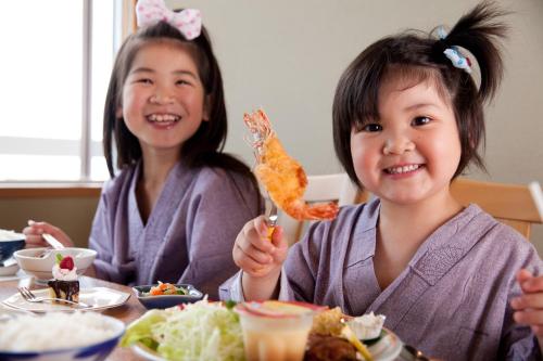two young girls sitting at a table eating food at Tenku Yubo Seikaiso in Beppu