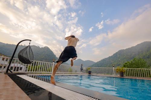 a man is jumping into a swimming pool at Zostel Plus Rishikesh, Mohanchatti in Rishīkesh