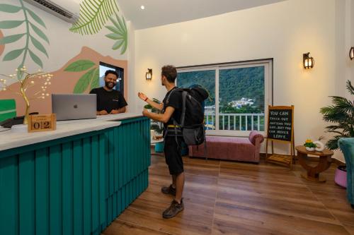 a man with a backpack standing at a counter at Zostel Plus Rishikesh, Mohanchatti in Rishīkesh