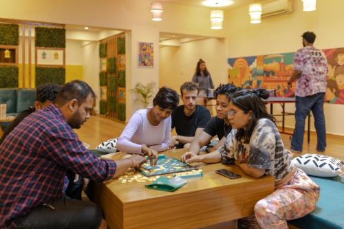 a group of people sitting around a table playing a board game at Zostel Plus Rishikesh, Mohanchatti in Rishīkesh