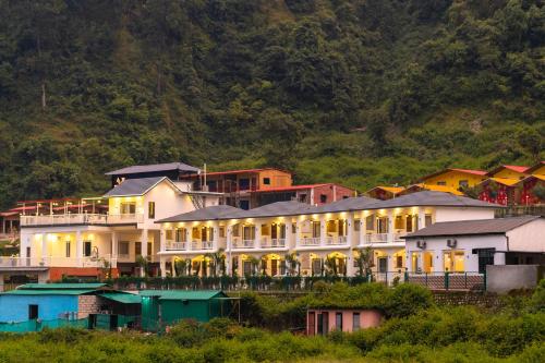 a large building on a hill with houses at Zostel Plus Rishikesh, Mohanchatti in Rishīkesh