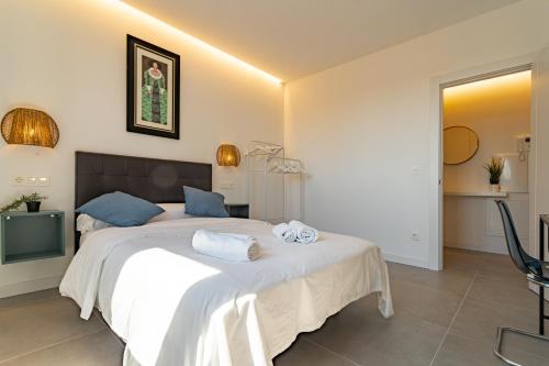 a bedroom with a large bed with white sheets and blue pillows at Edificio Santiago by Plaza Mayor Apartamentos in Valladolid