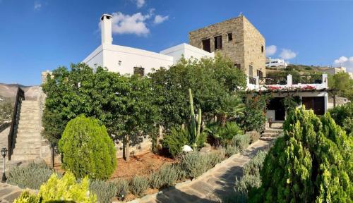 a church with a garden in front of a building at SYROU LOTOS Studios & Apartments in Kini