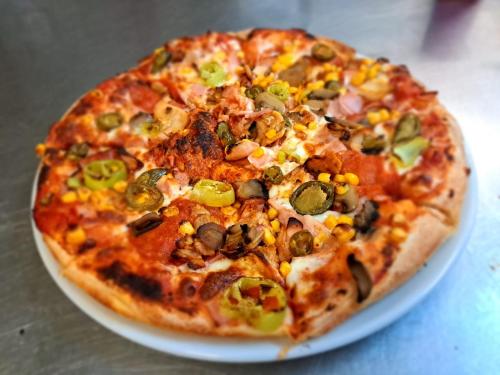 a pizza sitting on a plate on a table at Autohof 171 Hotel Hegyeshalom in Hegyeshalom