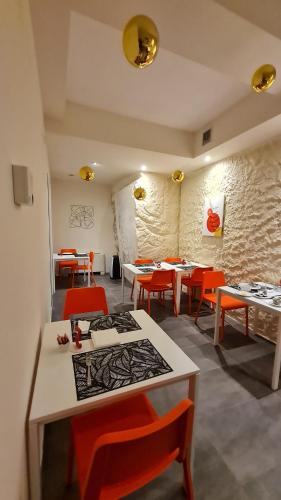 a dining room with tables and orange chairs at LITHOS ROOMs in Matera
