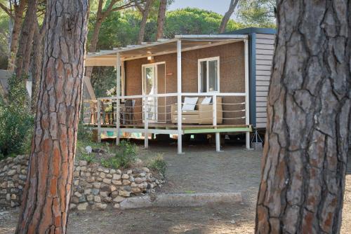 a tiny house with a porch in the woods at Camping Il Capannino Glamping Village in Marina di Bibbona