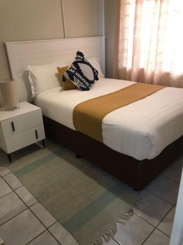 a bedroom with a large bed with a nightstand and a bed sidx sidx sidx at Lancy Apartments in Gaborone
