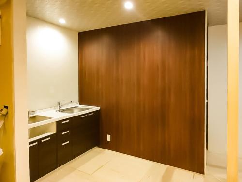 ein Badezimmer mit einem Waschbecken und einer Holztür in der Unterkunft Relak Guest House 登別 Station in Noboribetsu