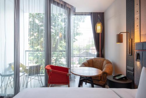 a hotel room with a bed and a table and chairs at Hotel Indigo Phuket Patong by IHG in Patong Beach