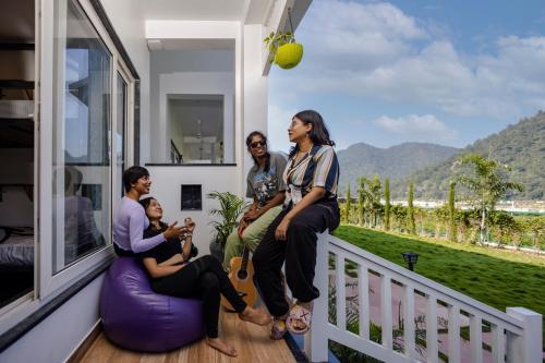 a group of people sitting on the balcony of a house at Zostel Plus Rishikesh, Mohanchatti in Rishīkesh