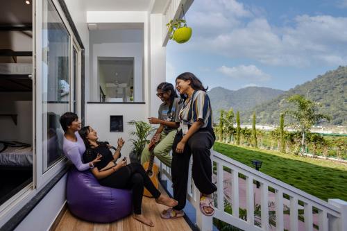 a group of people sitting on the porch of a house at Zostel Plus Rishikesh, Mohanchatti in Rishīkesh