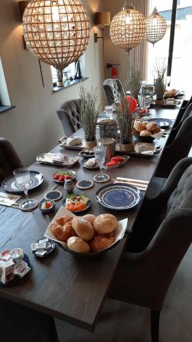 a long wooden table with plates of food on it at B&B de Maaskei in Guelle