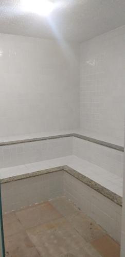 an empty bathroom with white walls and white tiles at STUDIO Mont Carmelo BA in Porto Seguro