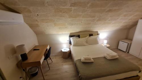 a small bedroom with a bed and a desk at LITHOS ROOMs in Matera