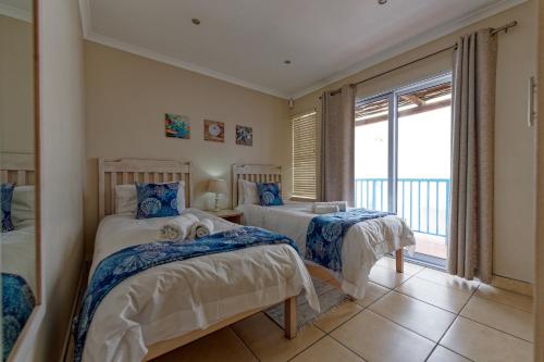 a bedroom with two beds and a balcony at Klein Sterretjie in Paternoster