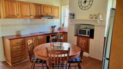 a kitchen with a table and chairs and a clock on the wall at Charming 100 yr old cottage in the heart of Moonta in Moonta