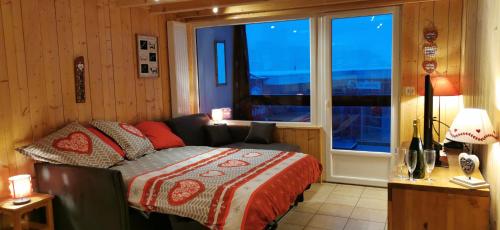 a bedroom with a bed and a large window at Immeuble le Champsaur in Orcières