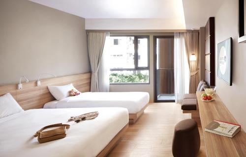 a hotel room with two beds and a window at Happy 3 in Bangkok