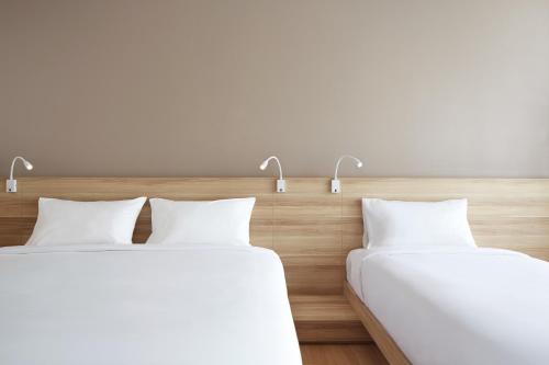 two beds in a hotel room with white pillows at Happy 3 in Bangkok